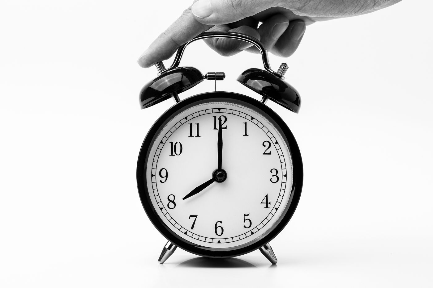 A hand reaching for the top control of a twin-bell alarm clock