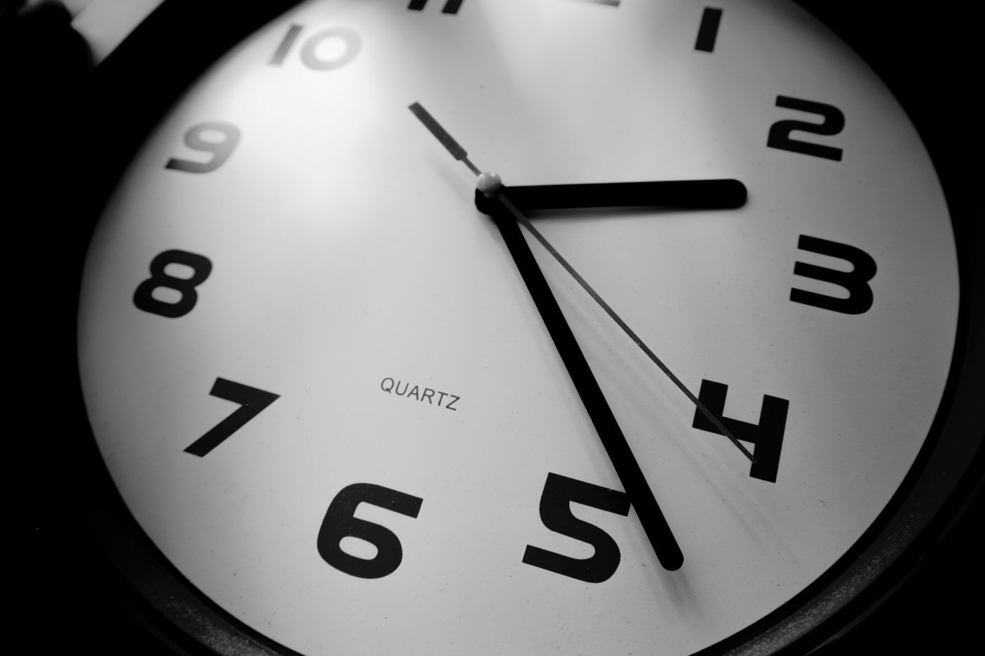 An angled close-up of a white quartz dial with black numerals