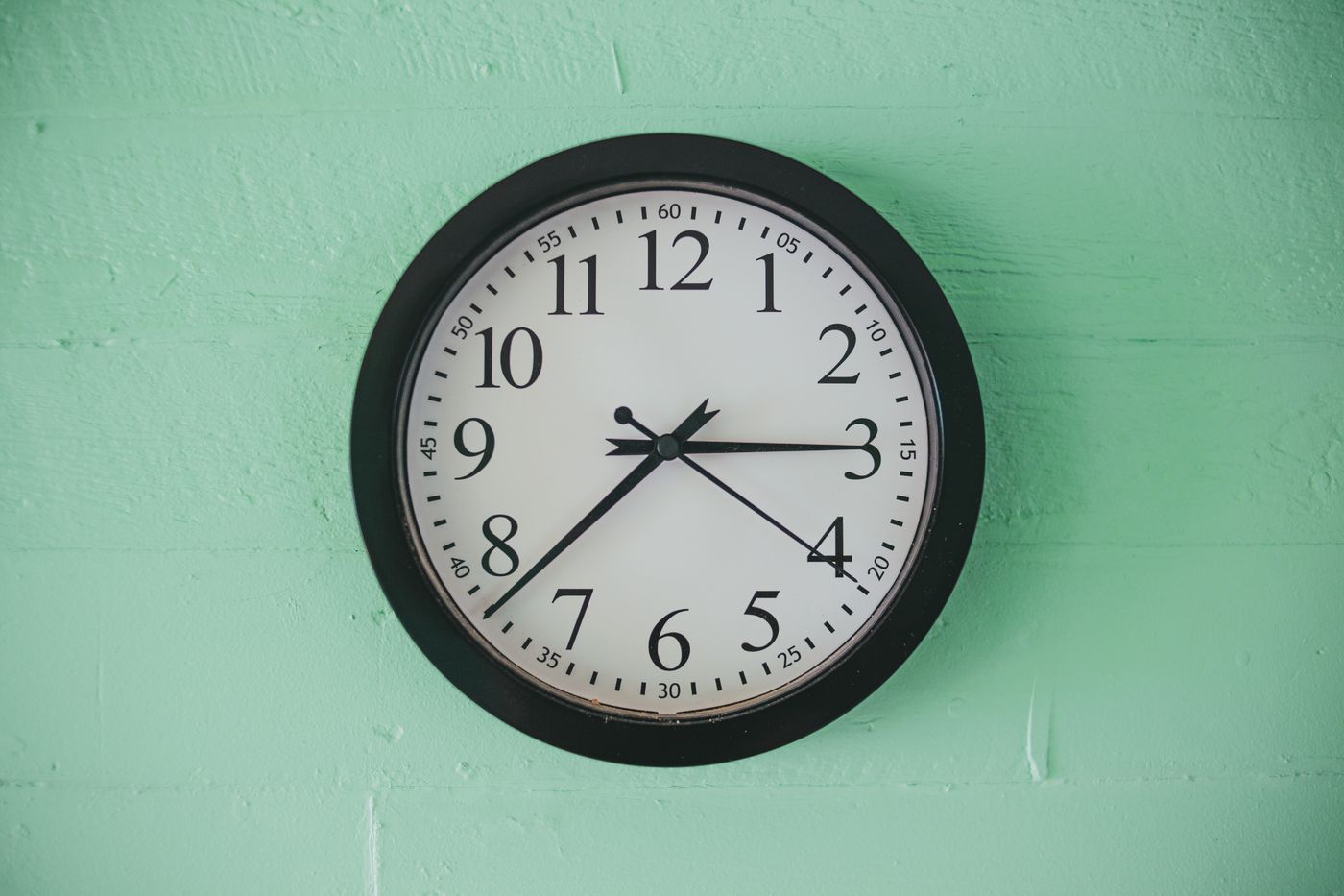 A black-framed quartz wall clock with a white numbered dial