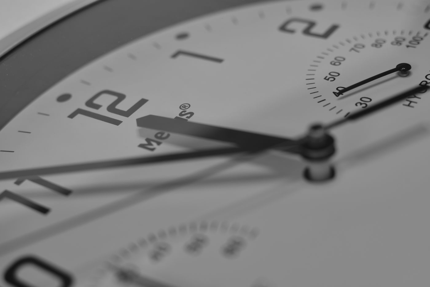 A close side view of clock hands above a numbered dial