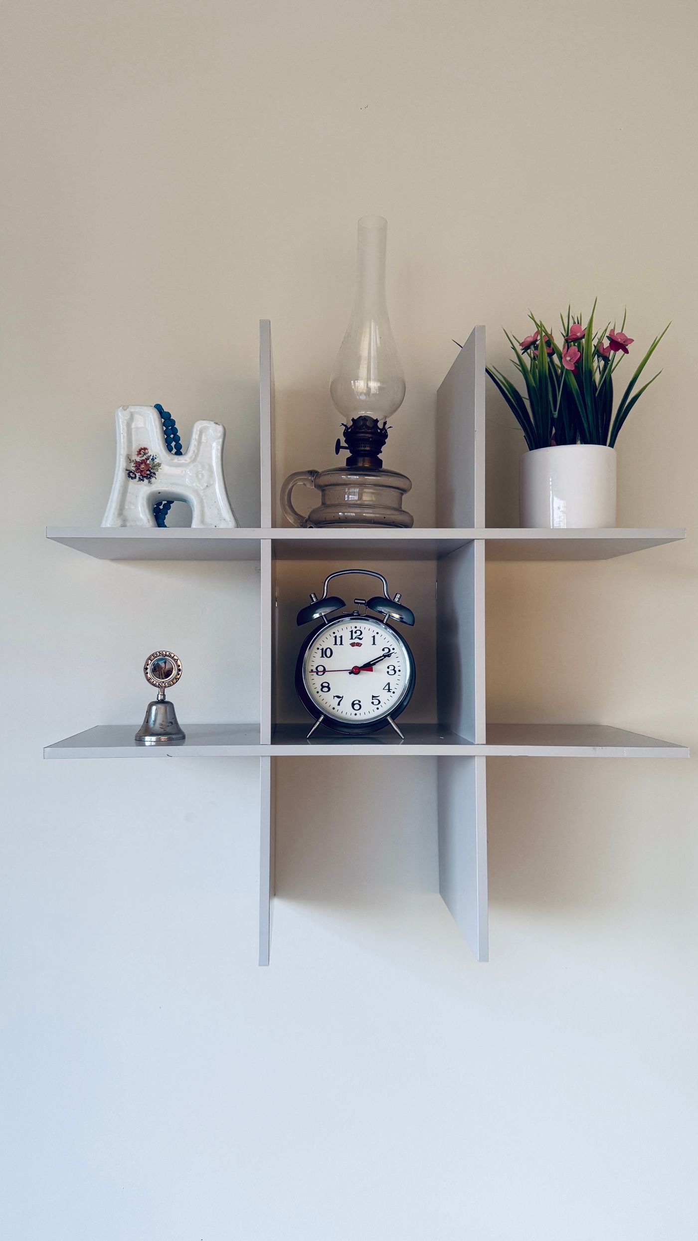 A small clock placed upright in a wall shelf compartment