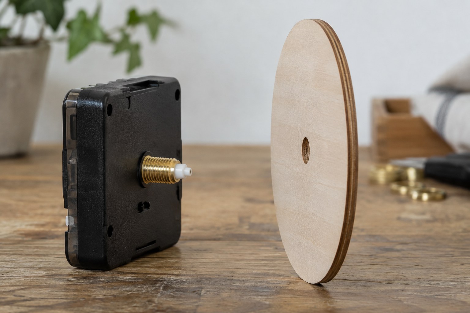 A quartz movement and threaded shaft beside a thin wooden dial blank