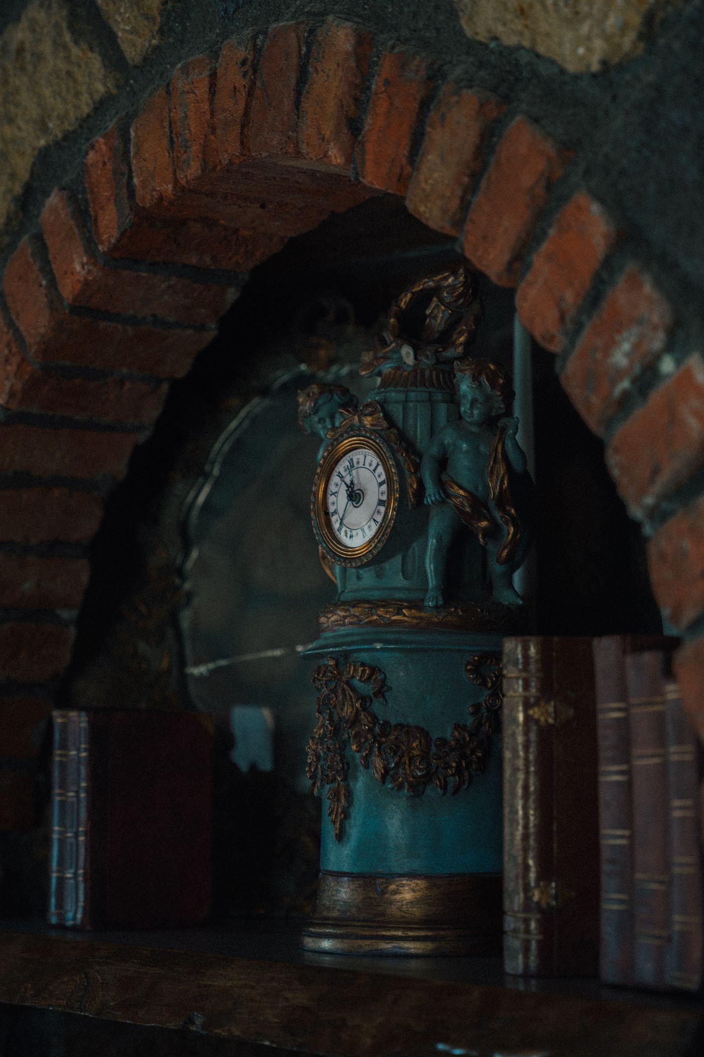 A weathered ornamental blue mantel clock in a brick recess