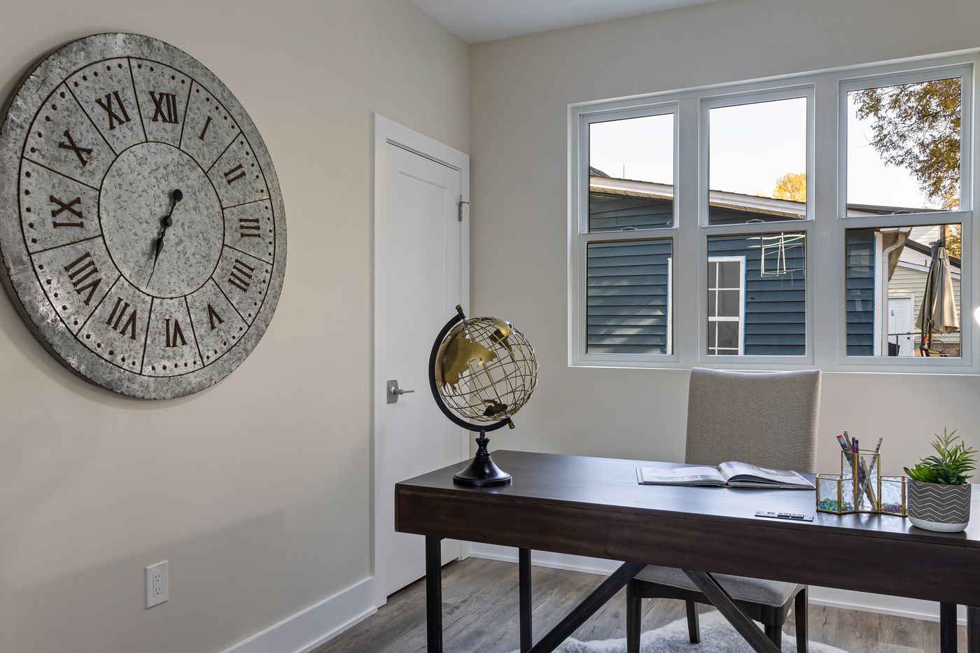 A large wall clock beside a desk in a home study