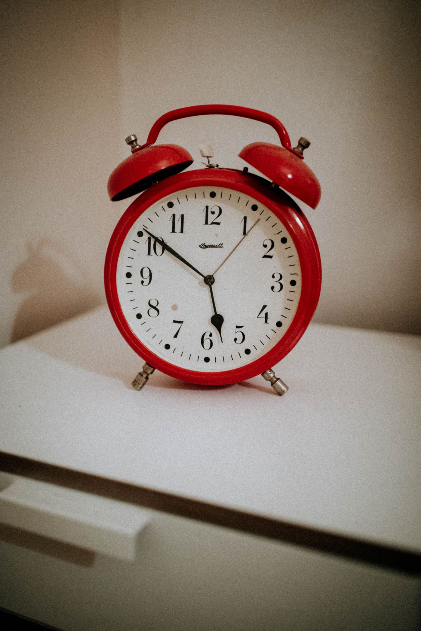 A red metal alarm clock with polished metal fittings